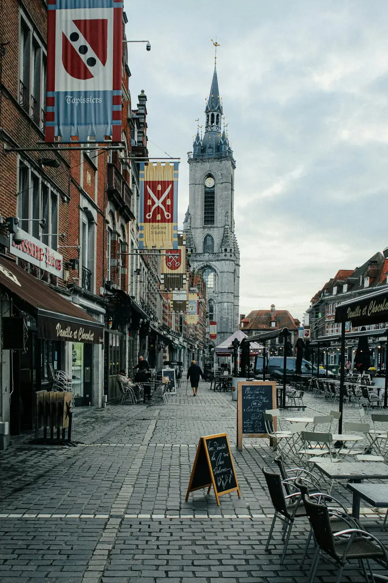 Rue pavée du centre de Tournai avec le beffroi à l’arrière-plan